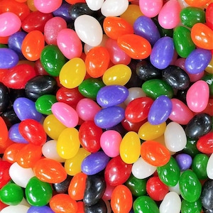 May include: A close-up image of a variety of jelly beans in various colors, including red, orange, yellow, green, blue, purple, pink, black, and white.