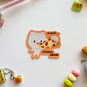May include: An orange sticker featuring a cartoon cat eating a slice of pizza. The pizza has red tomato sauce and melted cheese. Text on the sticker reads "mmm... CHEESY BREAD."