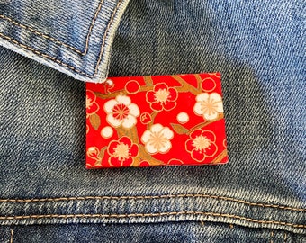 Unique Japanese Chiyogami washi pin brooch.  Handmade. White cherry blossoms on red with gold detail. Free shipping ready to ship
