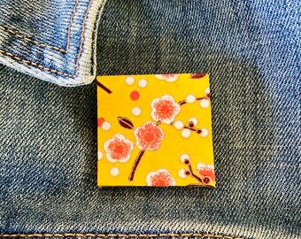Unique Japanese Chiyogami washi pin brooch.  Handmade. Pink and white cherry blossoms on yellow. Free shipping ready to ship