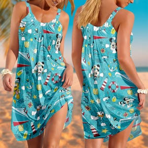 Könnte beinhalten: Hellblaues ärmelloses Kleid mit nautischem Thema und Cartoonfiguren. Das Kleid hat einen Rundhalsausschnitt und einen High-Low-Saum. Der Druck zeigt Mickey Mouse, Donald Duck, Anker, Boote und Muscheln.