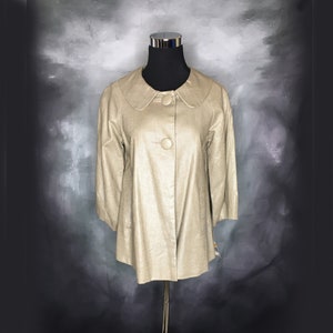 May include: A beige linen jacket with a peter pan collar and a single button closure. The jacket has a slightly fitted silhouette and three-quarter sleeves.