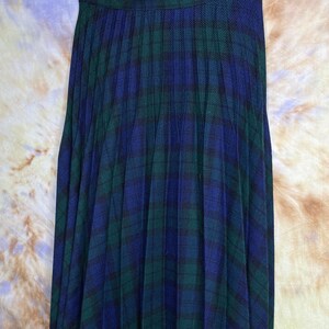 May include: A pleated skirt in a blue and green tartan pattern. The skirt is made of a soft, flowing fabric and has a classic, timeless style.