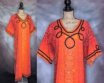 May include: A long, orange and yellow patterned dress with black trim around the neckline and sleeves. The dress has a loose fit and a V-neck.