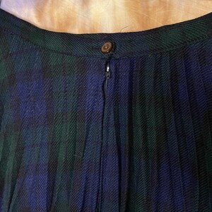 May include: A black, green and blue plaid skirt with a zip fastening. The skirt is pleated and has a waistband.