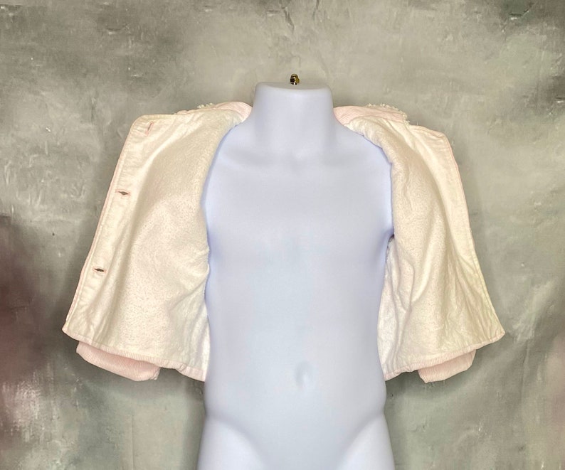 May include: A white fleece jacket with a pink trim. The jacket is open and the lining is visible.