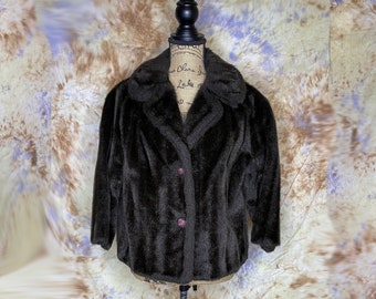 May include: A brown faux fur jacket with a collar and two buttons. The jacket is on a mannequin against a background of brown and blue.