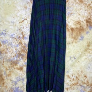 May include: A long, pleated skirt in a blue and green tartan pattern. The skirt has a waistband and is made of a soft, flowing fabric.