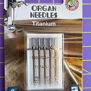 May include: A package of Organ Needles Titanium sewing machine needles. The package has the text "Top Quality Machine Needles" and "ORGAN NEEDLES Titanium". The needles are in a clear plastic case, with sizes 75/11, 80/12, and 90/14.