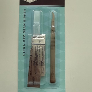 May include: A sewing seam ripper set in a clear plastic package. The package has the text "HAVEL'S SEWING" and "ULTRA-PRO SEAM RIPPER". The set includes a stainless steel handle seam ripper and four extra blades. The package also says "STAINLESS STEEL HANDLE 4 EXTRA BLADES SAFETY CAP".