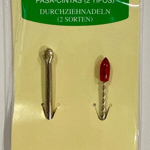 May include: Clover bodkins, two types, for threading ribbon or elastic. The package includes two bodkins: one with a silver finish and one with a red tip. The package also includes the text "BODKINS (2 TYPES)".