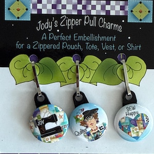 May include: Three Jody's Zipper Pull Charms with different designs. One charm says "JOY" with a sewing machine graphic. Another says "Quilter" with a woman's face. The third says "SEW Happy" with a heart graphic.