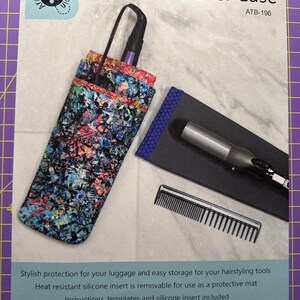 May include: A Hot Stuff Travel Case with a colorful abstract pattern. The case holds a hair styling tool, a comb, and a heat-resistant silicone insert. The finished case is approximately 6" x 13".