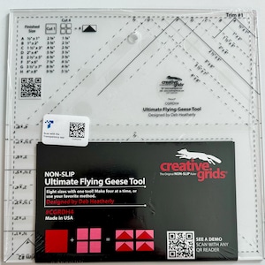 May include: A clear plastic ruler with a grid pattern and the text "Ultimate Flying Geese Tool" and "#CGRDH4". The ruler is designed for quilting and features eight different sizes of flying geese blocks. The ruler is made by Creative Grids.