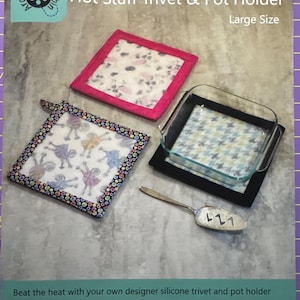 May include: A product image featuring a trivet and pot holder set. The set includes a pink-bordered trivet with a floral pattern, a black-bordered trivet with a blue and white pattern, and a black pot holder. A silver spatula is also included. The text reads "Hot Stuff Trivet & Pot Holder".