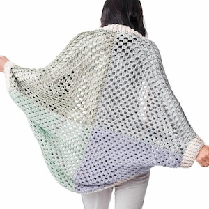 May include: A crochet cardigan featuring a color-blocked design with panels of light green, soft lavender, and muted grey. The garment is constructed with a classic granny square stitch pattern and finished with a cream-colored ribbed trim at the collar and cuffs.