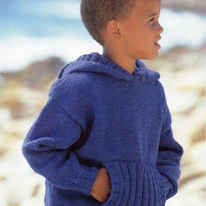 Op de afbeelding: Een blauwe gebreide trui met capuchon, lange mouwen en een kangoeroezak aan de voorzijde. De tekst Wash'n'Wear Crepe Double Knitting 4313 56-81cm 22-32" staat in de bovenhoeken. De trui is voorzien van een geribbelde zoom en boorden.