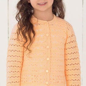May include: A peach-colored long-sleeve cardigan featuring a delicate openwork crochet pattern throughout the body and sleeves. The garment has a round neckline and is fastened down the center front with five matching round peach-colored buttons.