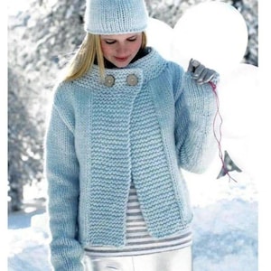 May include: A light blue knitted beanie and a matching long-sleeved cardigan with a textured garter stitch pattern. The cardigan features a high collar, two large round buttons at the neckline, and long sleeves. A striped shirt is worn underneath.