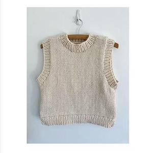 May include: A sleeveless knit sweater vest in a solid cream colour. The garment features a thick ribbed crew neckline and matching ribbed trim along the wide armholes and the bottom hem. The knit pattern is a standard stockinette stitch.