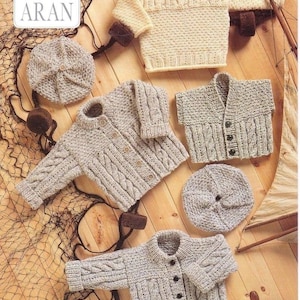 May include: A collection of knitted garments including a cream sweater, two grey cable-knit cardigans, a grey vest, and two matching grey berets. The items feature textured patterns and buttons, presented as a King Cole Aran knitting pattern set 2611.