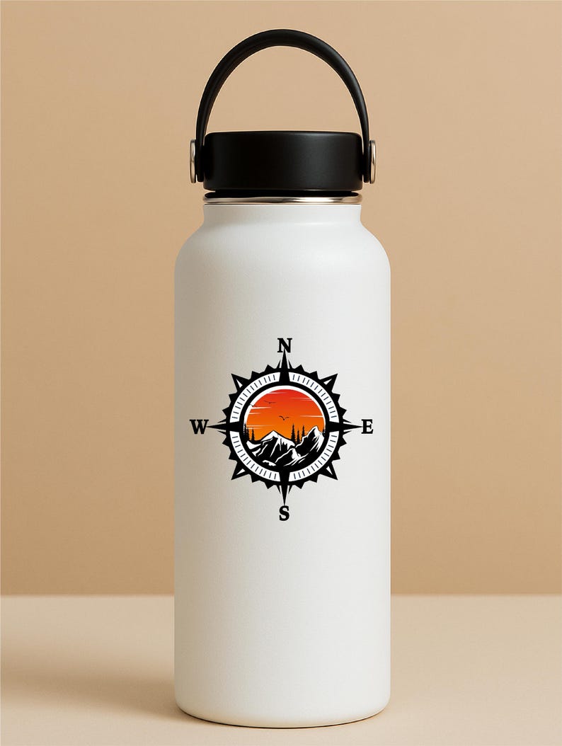 May include: White insulated water bottle with a black handle and lid. The bottle features a black and orange compass design with mountains, trees, and a sunset. The compass points to North, South, East, and West.