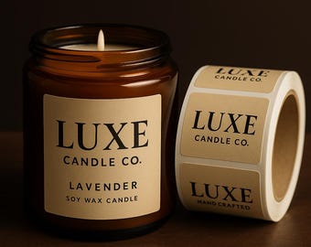 May include: A lit soy wax candle in an amber glass jar with a beige label reading LUXE CANDLE CO. LAVENDER SOY WAX CANDLE, positioned next to a roll of matching beige adhesive labels featuring the text LUXE CANDLE CO. and HAND CRAFTED.