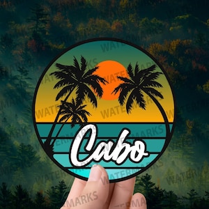 Puede incluir: Adhesivo circular con un diseño tropical. Muestra palmeras, una puesta de sol y la palabra "Cabo" en escritura blanca. El diseño utiliza tonos de turquesa, naranja y negro, evocando unas vacaciones en la playa.
