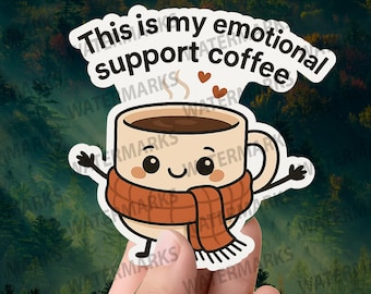 May include: A sticker featuring a cartoon coffee cup with a smiling face, wearing a brown scarf. The text "This is my emotional support coffee" is above the cup. Two small hearts are above the cup.