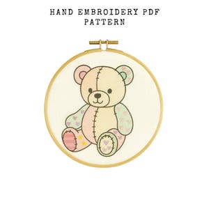 May include: Hand embroidery PDF pattern featuring a teddy bear design. The bear is in a wooden embroidery hoop. The bear is light pink, yellow, and green with heart and star accents. The text "HAND EMBROIDERY PDF PATTERN" is at the top.