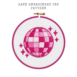 May include: A hand embroidery PDF pattern featuring a pink disco ball design with star accents. The design is set within a white fabric stretched in a round embroidery hoop with a pink border. The text "HAND EMBROIDERY PDF PATTERN" is at the top.