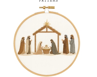 May include: Hand embroidery PDF pattern featuring a nativity scene. The design includes figures in various colors, a stable, and a star. The text "HAND EMBROIDERY PDF PATTERN" is at the top. The embroidery is set in a wooden hoop.