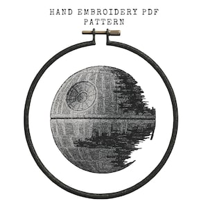 May include: Hand embroidery PDF pattern featuring a detailed Death Star design. The artwork is rendered in shades of gray and black, framed within a black embroidery hoop. The text "HAND EMBROIDERY PDF PATTERN" is at the top.