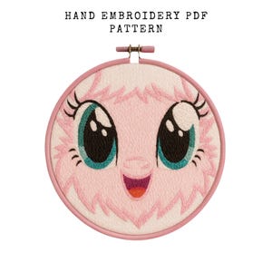 May include: A hand embroidery pattern featuring a cartoon face with large, teal eyes and a pink, smiling mouth. The design is set within a round, pink embroidery hoop. The text "HAND EMBROIDERY PDF PATTERN" is at the top.
