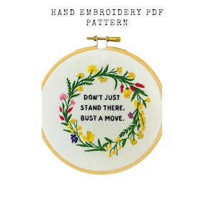 May include: Hand embroidery PDF pattern featuring a floral wreath design. The embroidery hoop displays a white fabric with a colorful floral wreath in yellow, red, pink, and purple. The text reads: "DON'T JUST STAND THERE. BUST A MOVE."