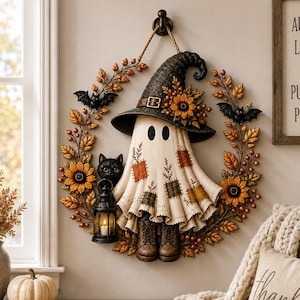 May include: A decorative wall wreath featuring a central ghost figure wearing a black witch hat with sunflowers, surrounded by autumn leaves, berries, and two black bats. The ghost wears brown boots and holds a black lantern with a black cat.