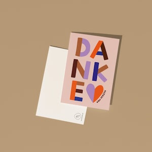 Puede incluir: Una tarjeta de felicitaci&oacute;n rosa claro con la palabra "DANKE" en letras de bloque coloridas y un coraz&oacute;n. Un sobre blanco est&aacute; al lado de la tarjeta sobre un fondo marr&oacute;n. El texto "VON HERZEN" tambi&eacute;n est&aacute; en la tarjeta.