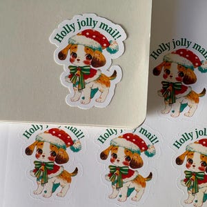 May include: A collection of stickers featuring a cartoon puppy wearing a Santa hat, a red and green scarf, and a red and white coat. The stickers have the text "Holly jolly mail!" printed on them. The puppy is white, brown, and tan.
