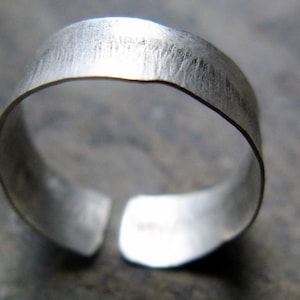 May include: A silver ring with a hammered finish. The ring is open and has a simple design.