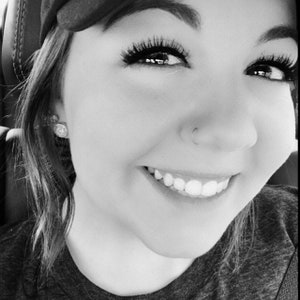 Può includere: Primo piano di un viso sorridente con gli occhi chiusi. La persona indossa un cappello nero e ha un piercing al naso.