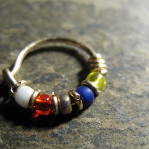May include: A gold hoop earring with a white, red, blue and yellow bead design.