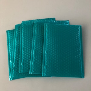May include: A stack of six teal blue bubble mailers. The mailers are made of a lightweight, durable material and are designed to protect items during shipping.