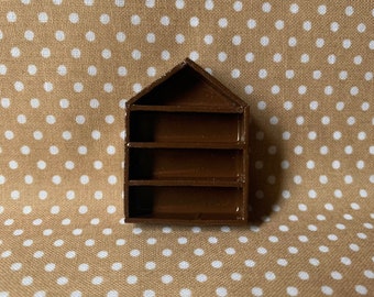 May include: A small brown wooden shelf with four shelves. The shelf is in the shape of a house.