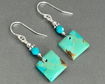 May include: A pair of silver earrings with turquoise stones and silver beads. The turquoise stones are square shaped and have a mottled green and blue color.
