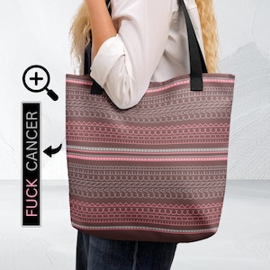 May include: A brown tote bag with a repeating pattern of pink, gray, and white lines and shapes. The bag has black handles and the text "FUCK CANCER" is printed on a black vertical rectangle.