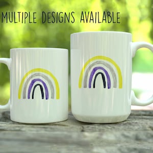 May include: Two white ceramic mugs with a yellow, gray, purple, and black rainbow design. The text "MULTIPLE DESIGNS AVAILABLE" is at the top of the image.