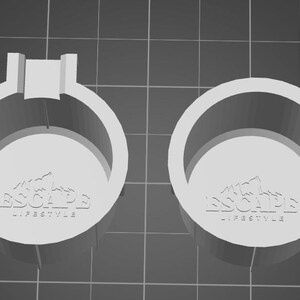 Peut inclure: Deux objets circulaires blancs avec le texte "ESCAPE LIFESTYLE" en relief en bas. L'un a une extension rectangulaire en haut. Les objets sont posés sur un fond quadrillé.