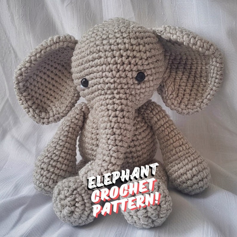 May include: A crocheted gray elephant toy with black eyes. The toy is sitting on a white surface and the text "Elephant Crochet Pattern!" is superimposed on the image.