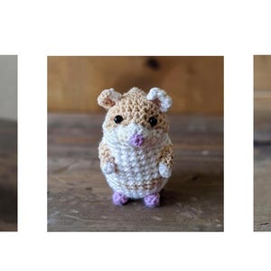 May include: Three crocheted hamster plushies with brown and white fur, pink noses, and purple feet. The plushies are sitting on a wooden surface.