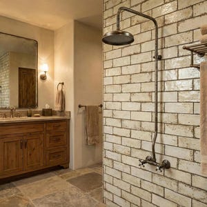 May include: A bathroom with a vintage aesthetic, featuring a large mirror and a wooden vanity. The shower area has a classic showerhead and fittings set against a brick-effect tiled wall. Towels are displayed on a rack, creating a spa-like atmosphere.